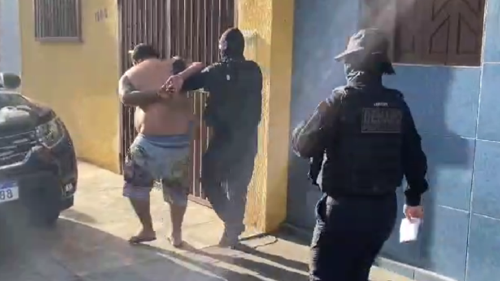 Homem sendo conduzido pela polícia após ser algemado / Foto: reprodução de vídeo