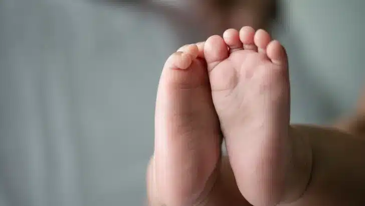 Baby feet in white bed.