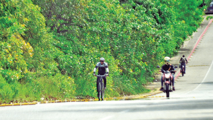 Ciclistas reclamam que precisam trafegar pela via dos carros e motos porque ciclovia está invadida pela vegetação - Foto:José Aldenir/Agora RN