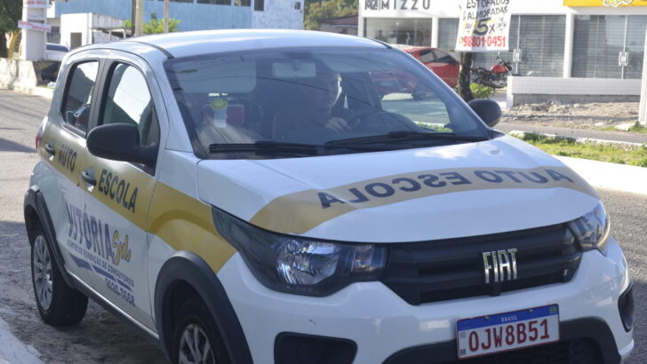 Carro de autoescola com faixa amarela estacionado em rua
