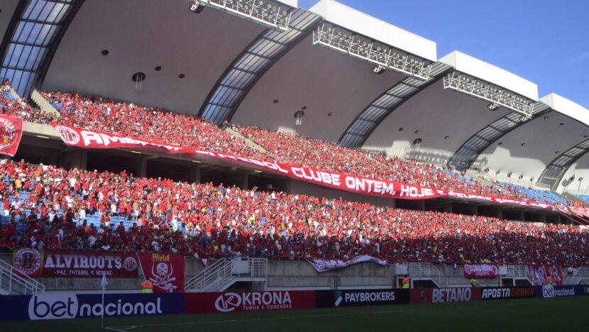 Torcedores do América com camisas vermelhas e brancas na arquibancada da Arena das Dunas