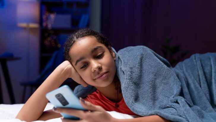 Adolescente usando o celular com um aplicativo de rede social aberto na tela