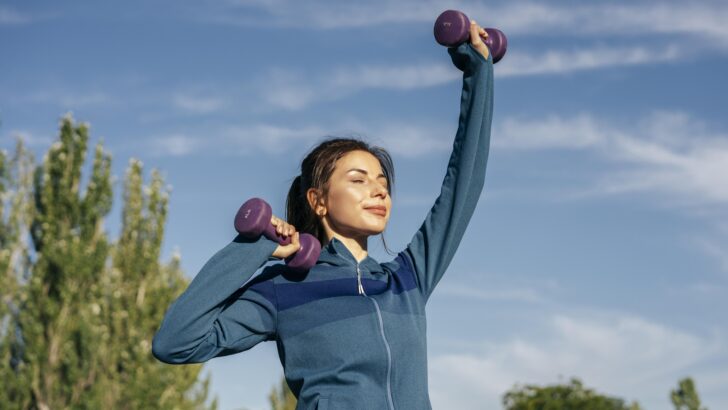 medium shot woman practicing with dumbbells
