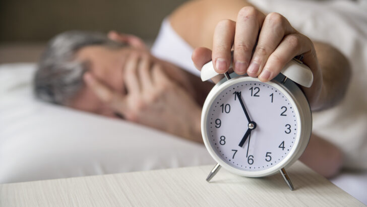 man lying bed tuRio Grande do Norteing off alarm clock moRio Grande do Norteing 7am attractive man sleeping his bedroom annoyed man being awakened by alarm clock his bedroom