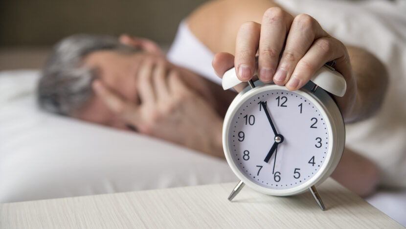 man lying bed tuRio Grande do Norteing off alarm clock moRio Grande do Norteing 7am attractive man sleeping his bedroom annoyed man being awakened by alarm clock his bedroom