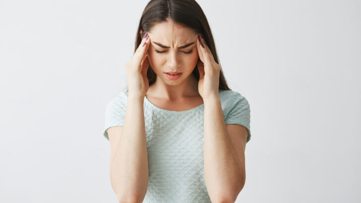 young beautiful brunette girl frowning touching temples headache isolated white background