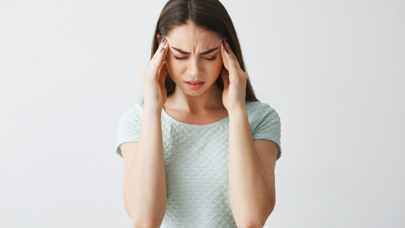 young beautiful brunette girl frowning touching temples headache isolated white background