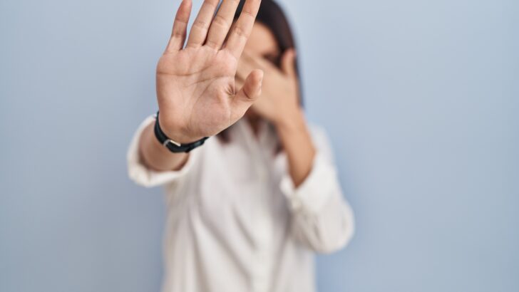 young hispanic woman standing white background covering eyes with hands doing stop gesture with sad fear expression embarrassed negative concept