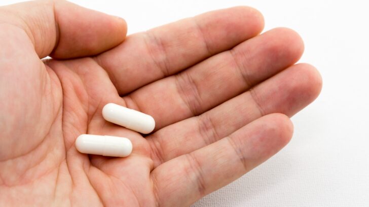 closeup shot person holding two white capsules