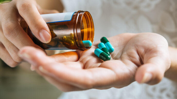woman s hand pours medicine pills out bottle