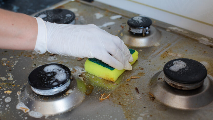 domestic female hand wearing gloves cleaning dirty stove after cooking using sponge washing woman housewife enjoying daily household closeup top view