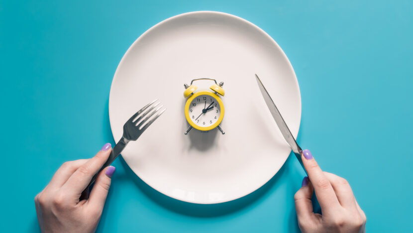 Como fazer jejum intermitente de forma segura | notícias do rio grande do norte hands holding knife fork alarm clock plate blue background Copia