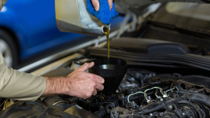 mechanic pouring oil into car engine