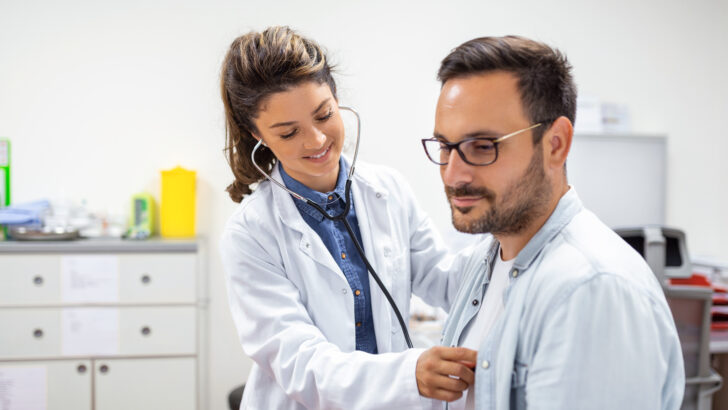 young doctor is using stethoscope listen heartbeat patient shot female doctor giving male patient check up Copia