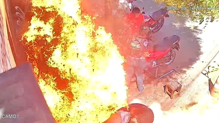 Imagem de câmera de segurança mostra explosão com chamas dentro de oficina mecânica, com pessoas e motocicletas próximas ao local