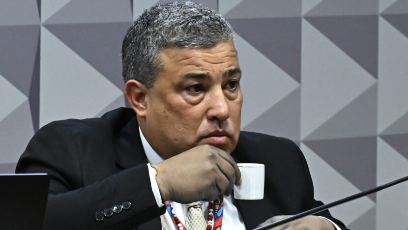 Carlos Roberto Ferreira Lopes durante sessão, vestindo terno e segurando uma xícara