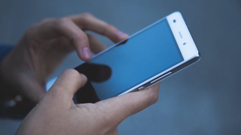 Pessoa segura e utiliza um telefone celular com tela ligada