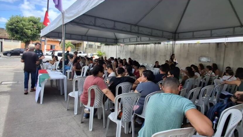 Trabalhadores reunidos em cadeiras sob uma tenda durante mobilização de servidores da saúde