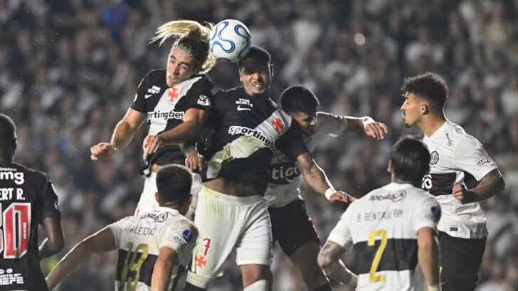 Jogadores de Vasco e Olimpia disputam a bola pelo alto durante partida de futebol em São Januário