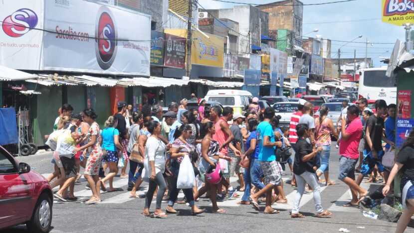 Movimentação de consumidores e veículos em área comercial com lojas e estabelecimentos