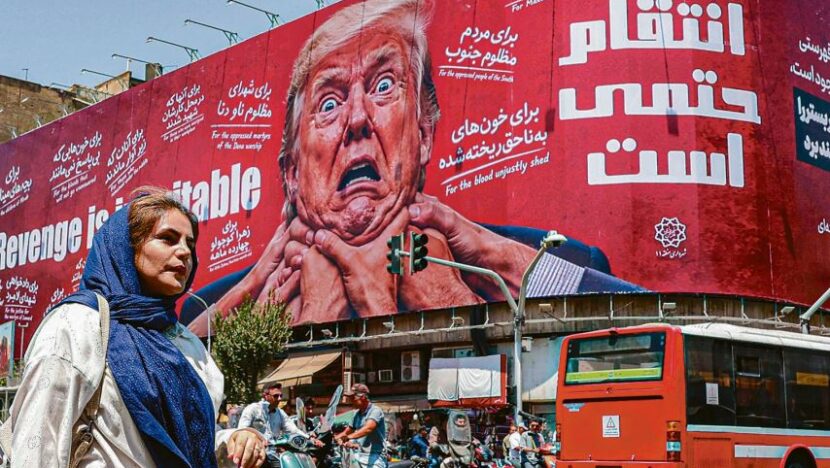 Mulher passa diante de mural vermelho com representação de Donald Trump, enquanto veículos circulam pela rua
