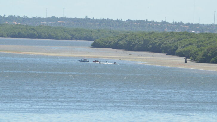 Embarcações navegam pelo rio Potengi em trecho cercado por manguezais, em Natal
