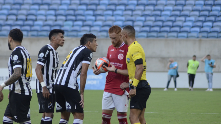 ogadores de ABC e América-RN reunidos com o árbitro no gramado da Arena das Dunas durante partida