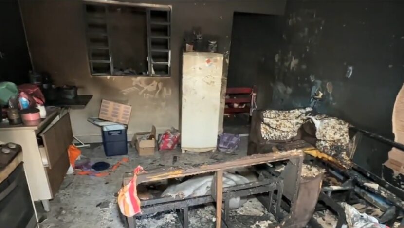 Interior de residência com paredes, móveis e objetos danificados pelo fogo após incêndio