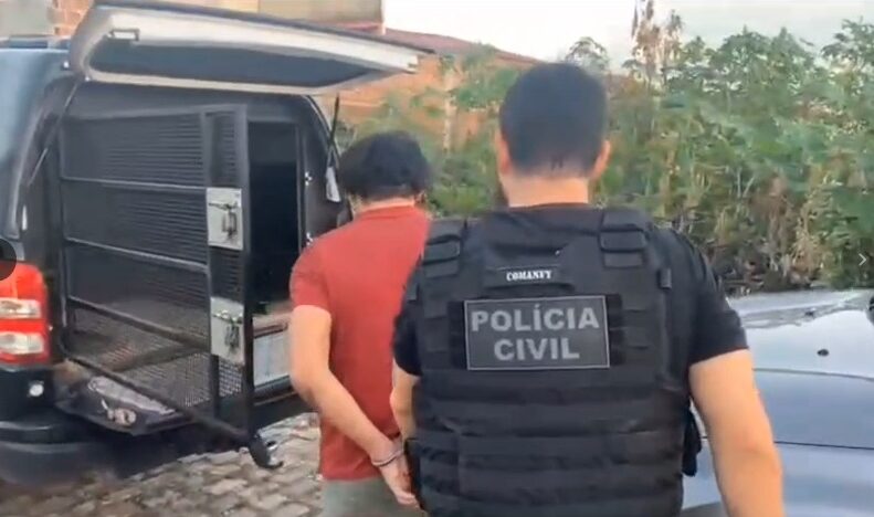 Policial civil acompanha homem algemado em direção a uma viatura durante cumprimento de mandado de prisão