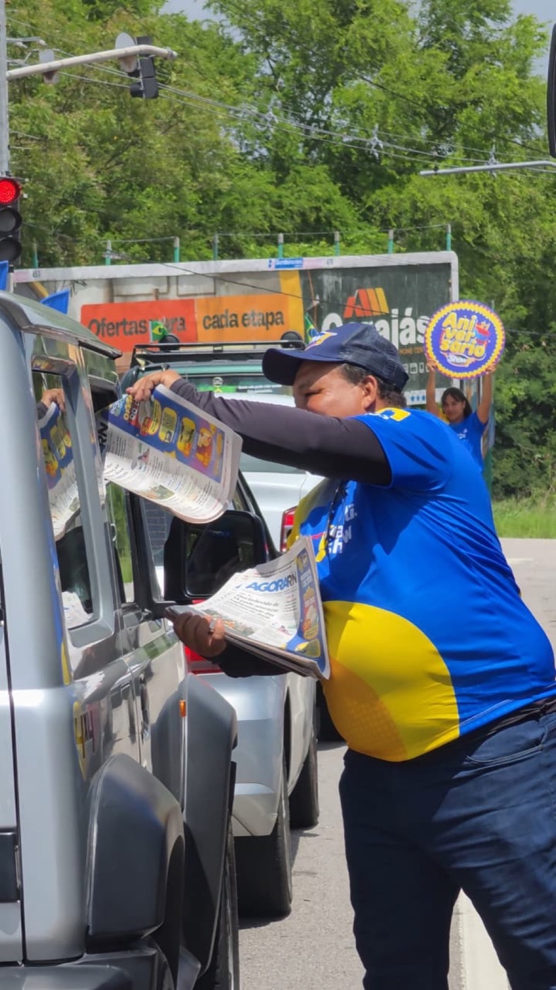 Promotora entrega o Agora RN durante ação de rua do Super Show