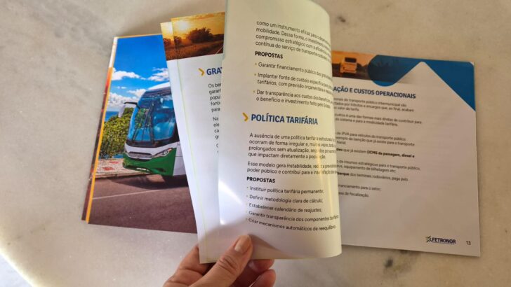 Pessoa folheia publicação da Fetronor aberta nas páginas sobre política tarifária e custos operacionais
