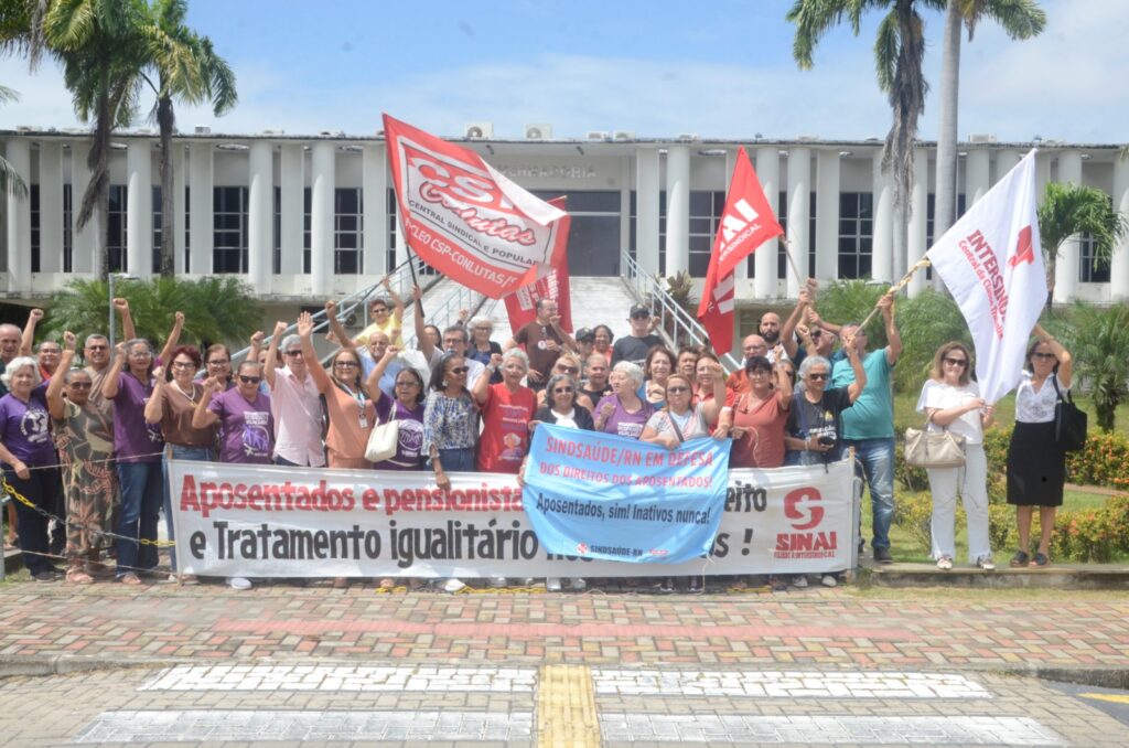 Manifestantes exibem uma faixa durante protesto de aposentados e pensionistas na rampa da GoveRio Grande do Norteadoria do Rio Grande do Norte