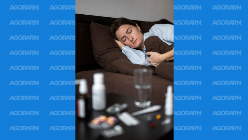 Mulher dorme deitada em uma cama enquanto medicamentos e um copo com água aparecem em primeiro plano