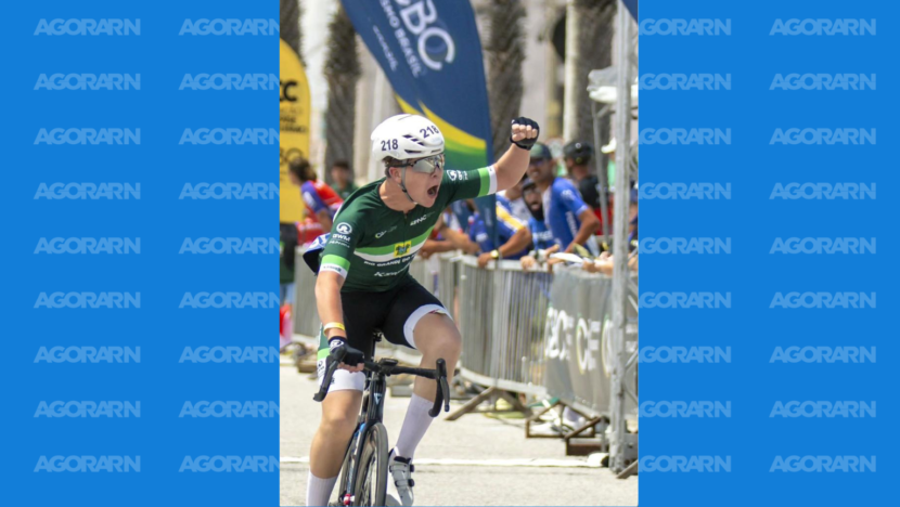 Ciclista com uniforme do Rio Grande do Norte pedala e comemora com o braço erguido durante competição