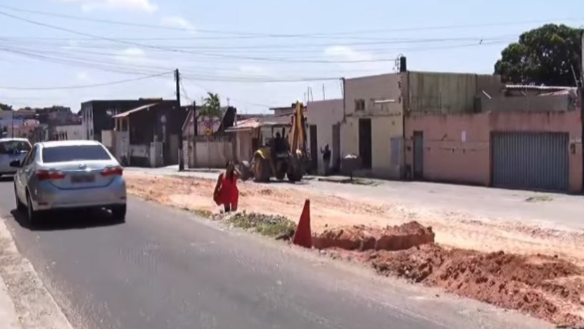 Trecho da Avenida Jerônimo Câmara em obras, com retroescavadeira, cones de sinalização e veículos circulando pela via