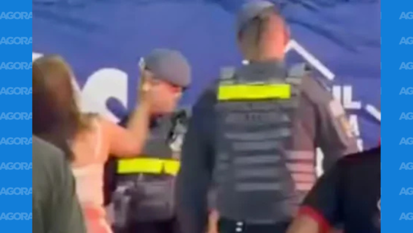 Imagem mostra mulher de roupa branca com o braço levantado diante de policiais durante uma confusão
