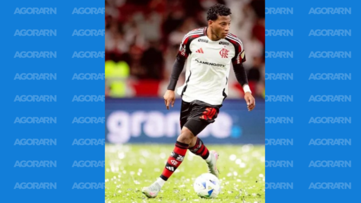 Jogador com uniforme do Flamengo conduz a bola no gramado durante uma partida