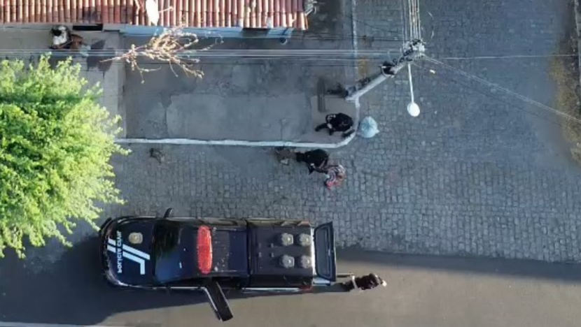 Vista aérea mostra viatura e agentes da Polícia Civil durante ação em uma rua
