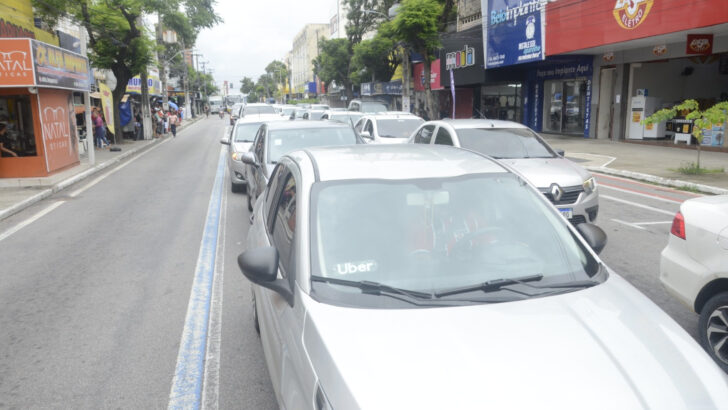 Carros de aplicativo e táxis, atendidos pelo Move Brasil, estacionados em rua comercial de Natal
