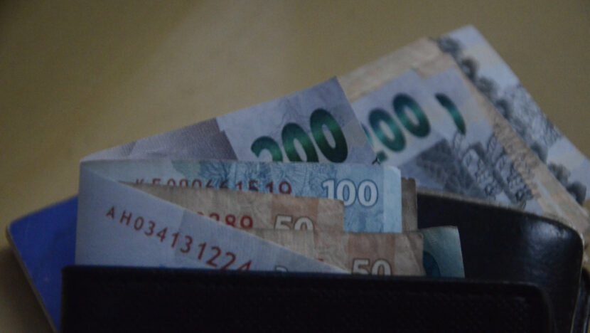 Cédulas de real de 200, 100 e 50 saindo de uma carteira de couro.