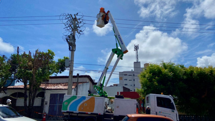 Trabalhador atua em poste da rede elétrica com auxílio de caminhão equipado com cesto aéreo durante serviço de manutenção