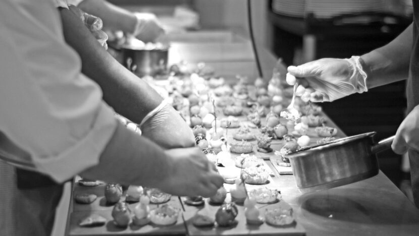 Trabalhadores do setor de serviços preparando alimentos em uma cozinha profissional