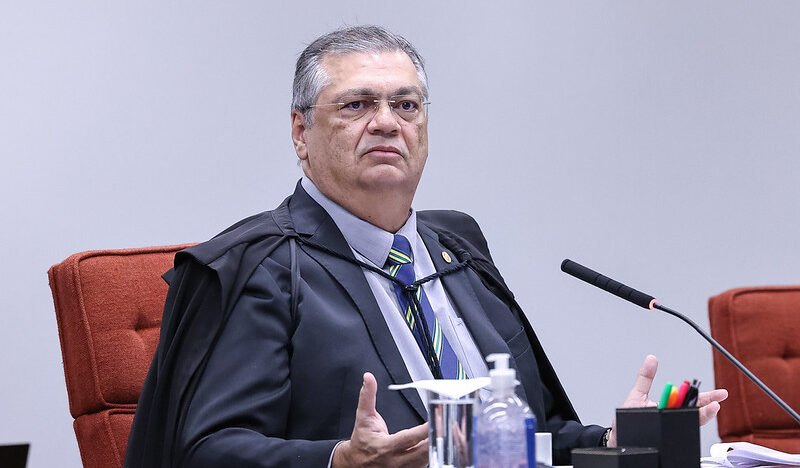 Flávio Dino sentado na bancada do Supremo Tribunal Federal, usando toga e diante de um microfone