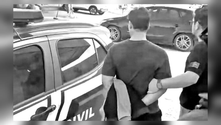 Guarda municipal é conduzido por policial civil ao lado de uma viatura