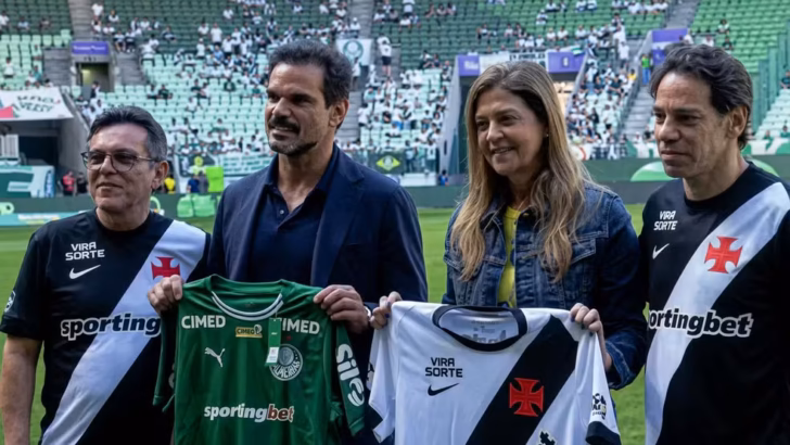 Quatro pessoas posam em campo de futebol segurando camisas do Palmeiras e do Vasco