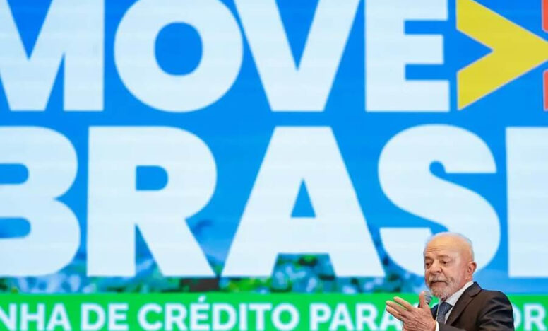 residente Lula fala ao público diante de um painel azul com a inscrição “Move Brasil” em letras brancas