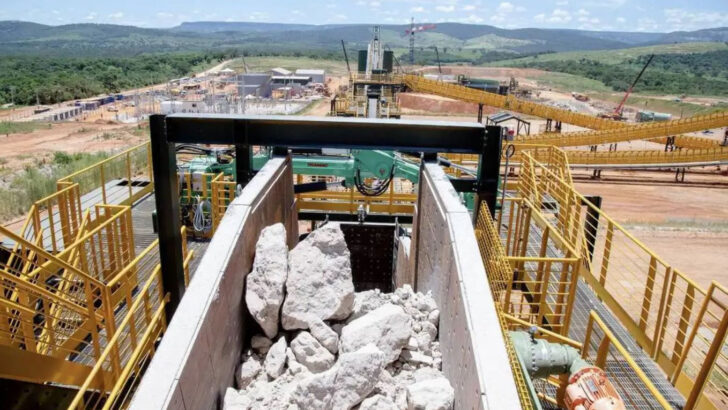 Minério de lítio, um dos minerais críticos, britado em calha de alimentação com a planta de beneficiamento ao fundo
