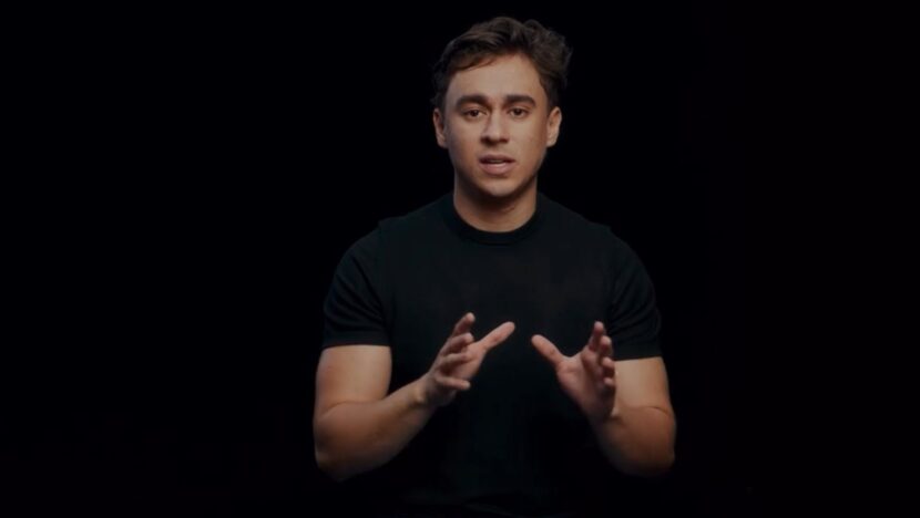 Nikolas Ferreira, vestido de preto, fala e gesticula diante de um fundo escuro