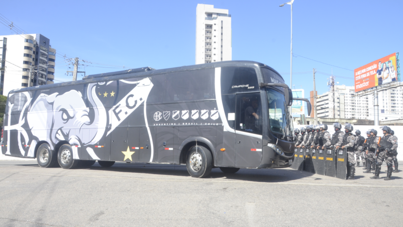 Ônibus preto do ABC passa diante de policiais militares com capacetes, escudos e equipamentos de proteção