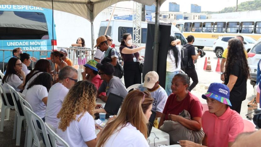 Pessoas em situação de rua recebem atendimento em mesas instaladas sob uma tenda durante mutirão em Natal